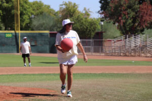 Person playing kickball on a sunny field.