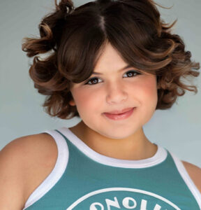 Young person smiling with curly hair.